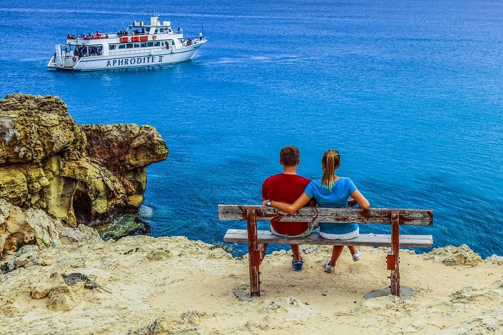 couple with view overlooking cliff and boat in the ocean